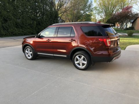2016 Ford Explorer - A copper SUV is parked on a concrete driveway with trees and a house in the background.