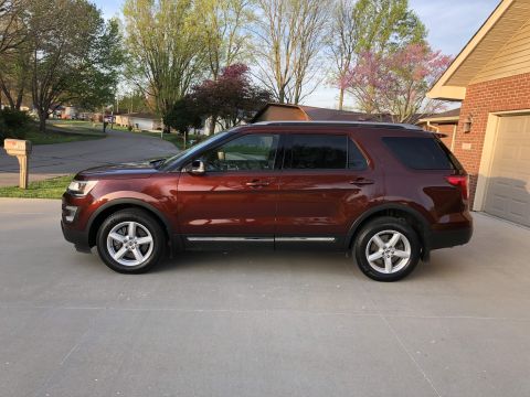 2016 Ford Explorer - A red 2016 Ford Explorer is parked in front of a house on a sunny day.