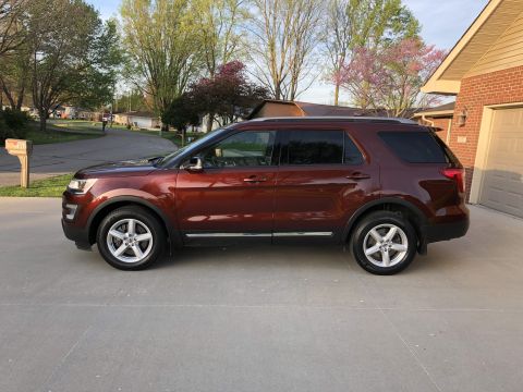 2016 Ford Explorer - A red 2016 Ford Explorer is parked in front of a brick house on a sunny day.