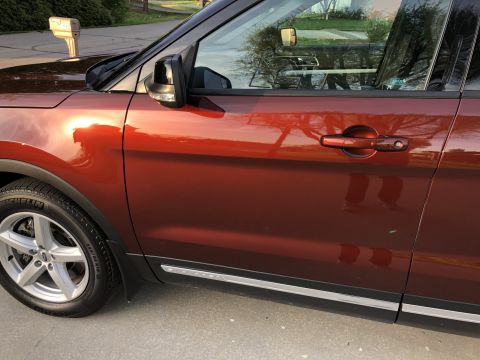 2016 Ford Explorer - Side view of an orange 2016 Ford Explorer, highlighting its door and wheel.