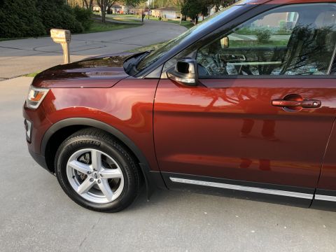 2016 Ford Explorer - 2016 Ford Explorer shown from the side, parked on a paved surface with a residential street in the background.