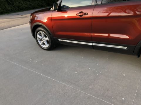 2016 Ford Explorer - The side profile of a red SUV is shown, reflecting the surroundings in its paint.