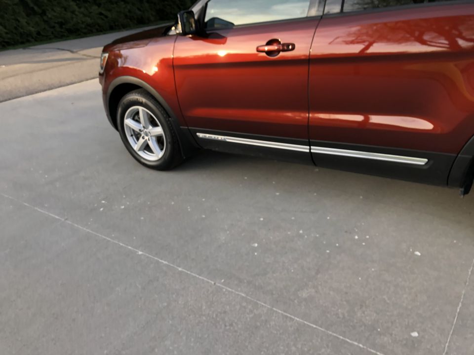 Side view of a red SUV with chrome trim along the bottom of the doors