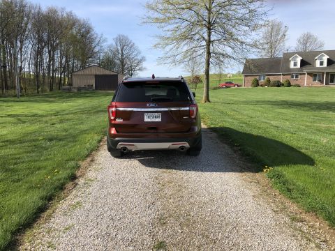 2016 Ford Explorer - A red 2016 Ford Explorer is parked on a gravel driveway in front of a house and barn.
