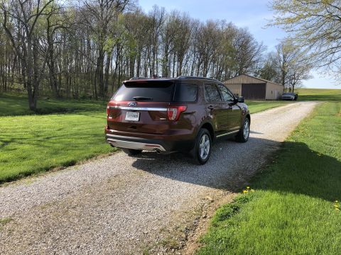 2016 Ford Explorer - The rear of a red 2016 Ford Explorer is visible on a gravel driveway, with a wooded area and a barn in the background.