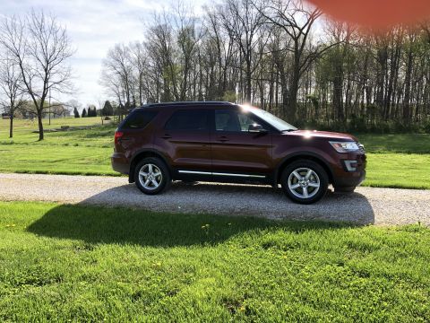 2016 Ford Explorer - A maroon SUV is parked on a gravel driveway on a sunny day.