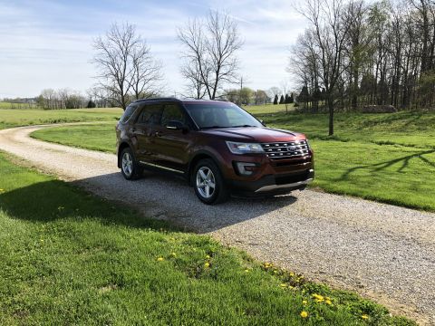 2016 Ford Explorer - This maroon 2016 Ford Explorer is parked on a gravel driveway surrounded by green grass and trees.