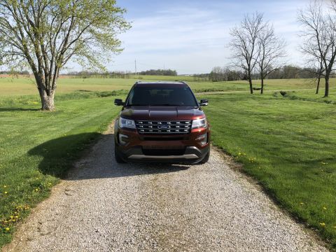 2016 Ford Explorer - A red 2016 Ford Explorer is shown from the front on a gravel driveway with a rural landscape in the background.