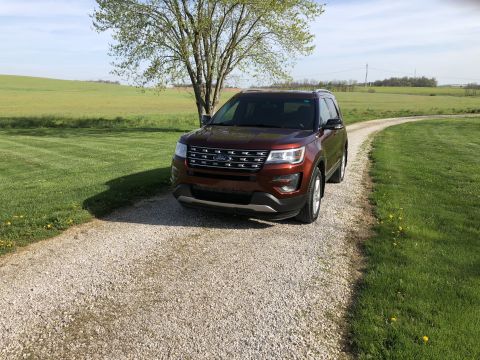 2016 Ford Explorer - A brown Ford Explorer is parked on a gravel driveway next to a grassy field.