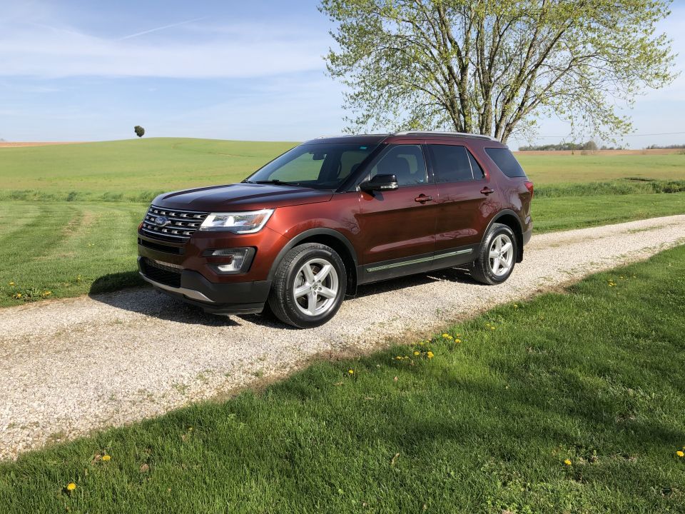 Brown 2016 Ford Explorer parked on a gravel driveway next to a grassy field