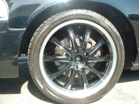 1999 Ford Crown Victoria - Aftermarket wheel and tire assembly on a vehicle. The brake system is visible through the wheel spokes.