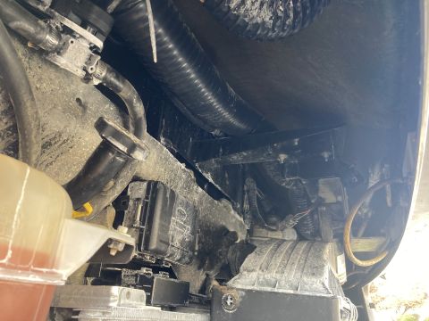 2015 Ford F-550 - Close-up view of various engine bay components, including hoses, wiring, and a fuse box, with no visible year identification.