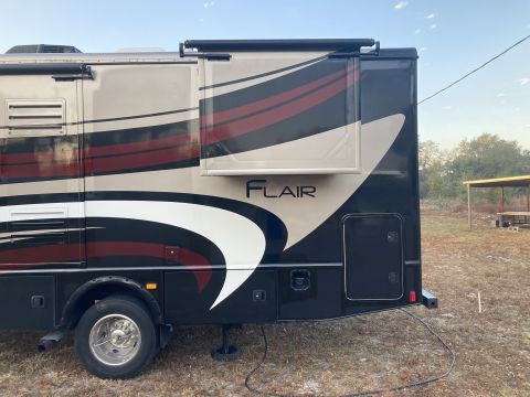 2015 Ford F-550 - Side view of a motorhome with a "FLAIR" decal and extended awning.