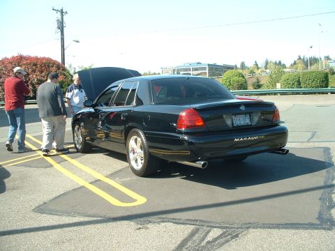 1999 Ford Crown Victoria - Black 2003 Mercury Marauder with hood open and custom wheels, seen at a meet.