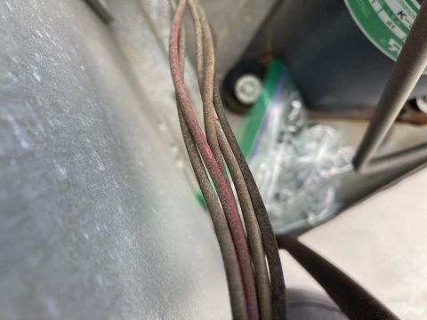 2015 Ford F-550 - Macro view of a bundle of automotive wires with brown and pink-striped insulation against a metal surface with hardware behind.