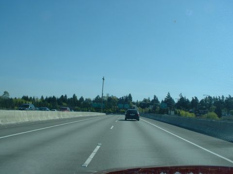 1999 Ford Crown Victoria - A car travels down a highway under a clear blue sky, with other vehicles visible in the distance.