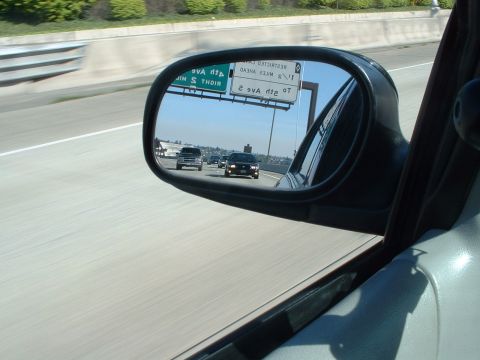 1999 Ford Crown Victoria - Traffic moves along a highway, as seen through the side mirror of a vehicle.