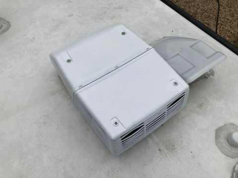 2015 Ford F-550 - white plastic RV rooftop air conditioner cover with vented end mounted on a white roof surface.