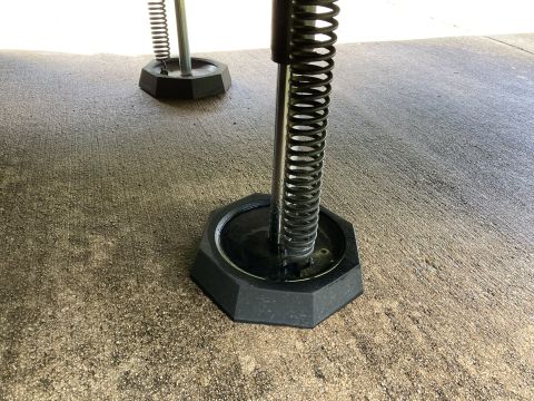 2015 Ford F-550 - Close-up of RV leveling jacks with visible springs and hexagonal bases on a concrete surface.