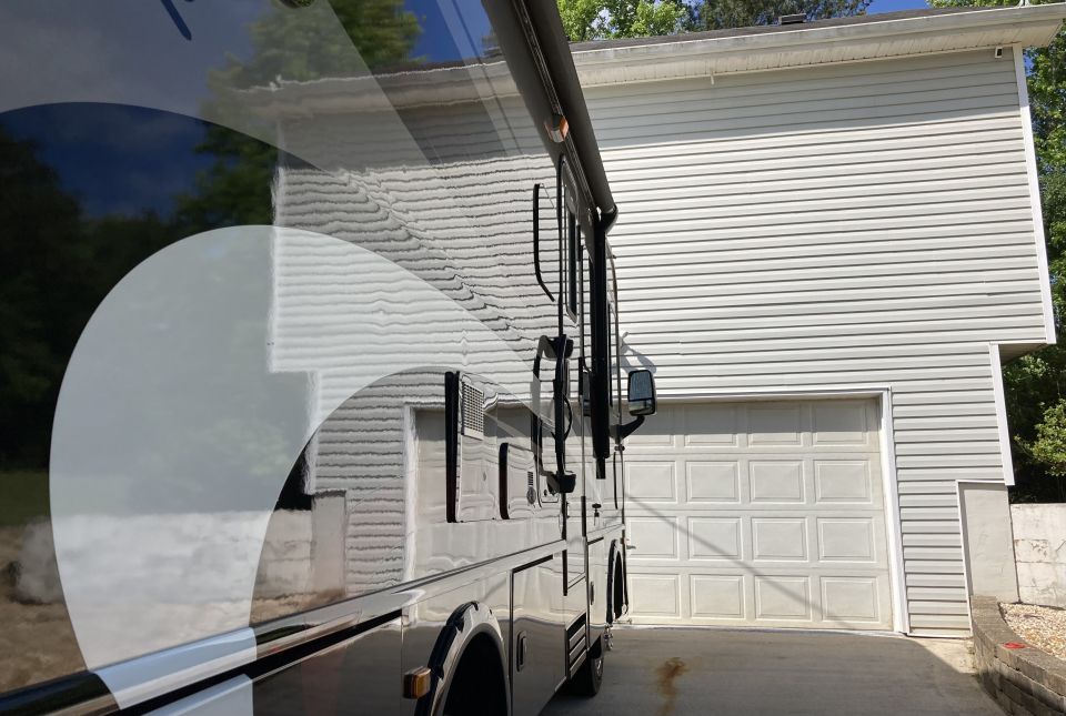 Side view of a motorhome parked next to a garage