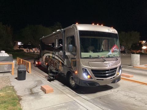 2015 Ford F-550 - A motorhome is parked at night, with its entry steps extended and lights on.