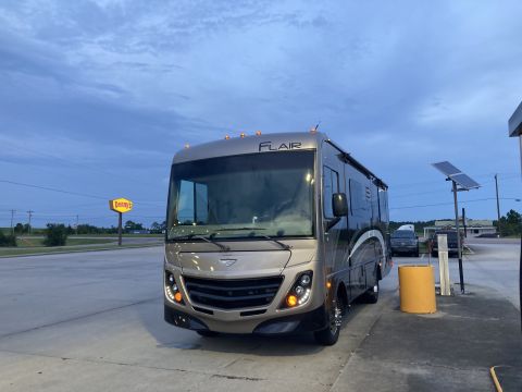 2015 Ford F-550 - A tan motorhome with 'FLAIR' badging is parked at a gas station.