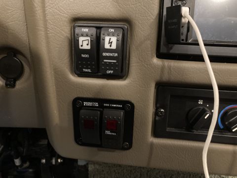 2015 Ford F-550 - Interior dashboard view showing various control switches for radio, generator, and cameras, alongside climate controls.
