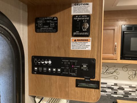 2015 Ford F-550 - This interior view shows a control panel with switches for room slideout, bed lift, and generator functions, along with various indicator l…