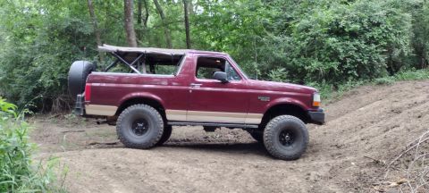 1996 Ford Bronco - This maroon 1996 Ford Bronco, tan trim and a soft top, navigates an off-road trail.