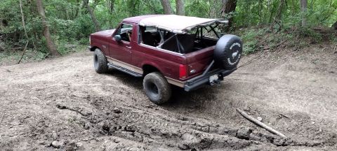 1996 Ford Bronco - 1996 Ford Bronco navigating a muddy off-road trail.