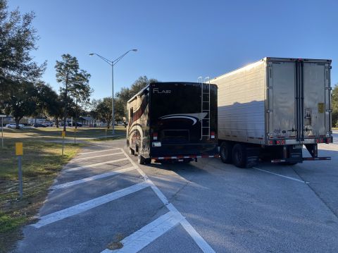 2015 Ford F-550 - A motorhome is parked next to a semi-trailer under a clear blue sky.