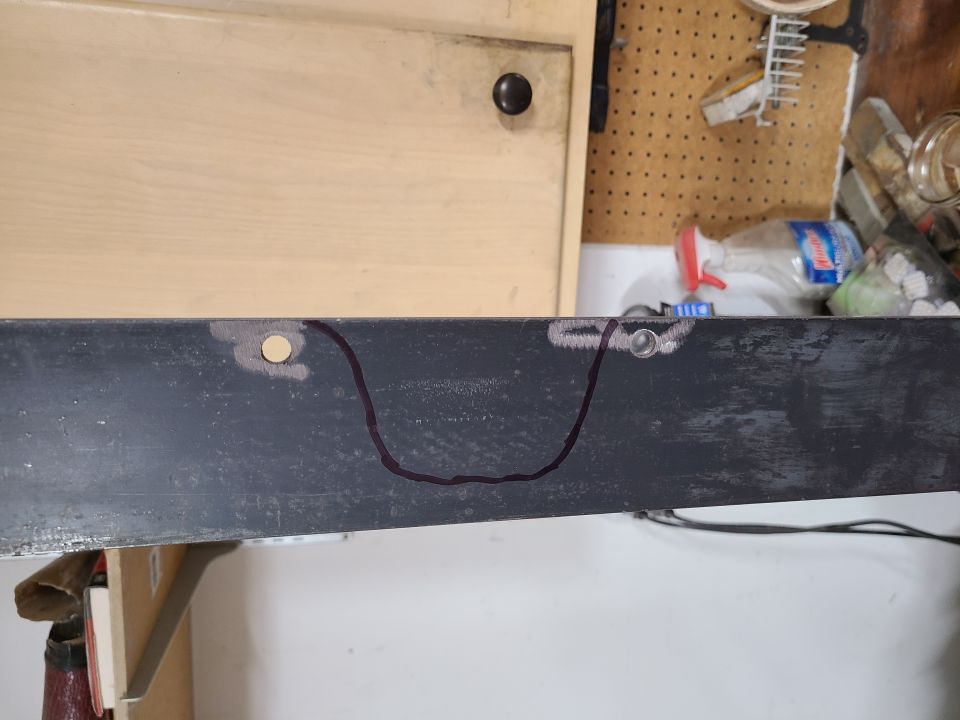 Metal bracket with a drawn outline and two holes, one with a bolt
