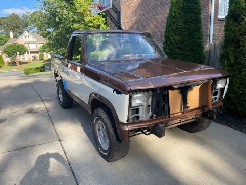 1984 Ford Bronco - This 1984 Ford Bronco is shown from a three-quarter front angle, missing its grille and in need of repair.