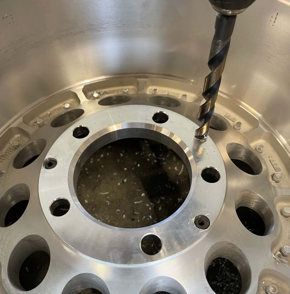 Drilling a hole in a silver alloy wheel with a drill bit