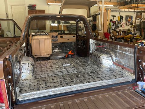 1984 Ford Bronco - Interior view of a brown Ford Bronco undergoing sound deadening installation in a garage.