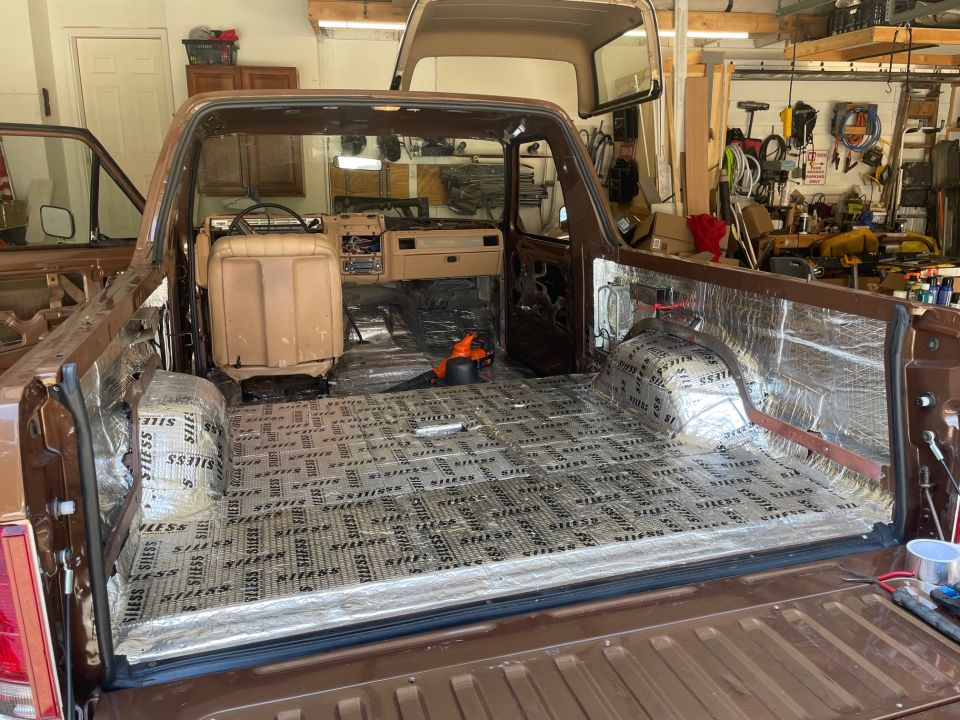 Brown Ford Bronco interior with sound deadening material on the floor and bed, doors removed