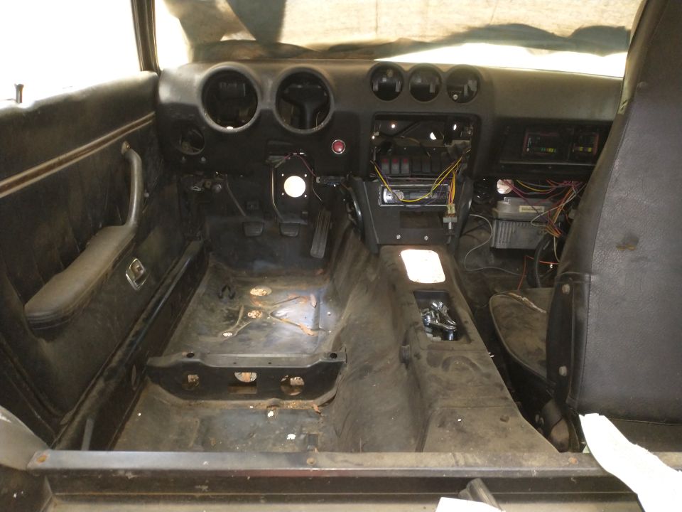 Interior of a car with seats removed, dashboard exposed, and wiring visible