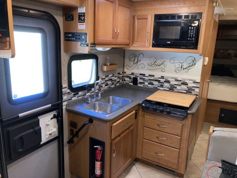 2015 Ford F-550 - Interior view of an RV kitchen a sink, stove, and microwave.
