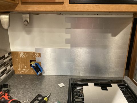 2015 Ford F-550 - A kitchen backsplash is under renovation with silver subway tiles and exposed electrical wiring.