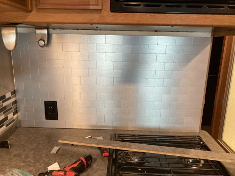 2015 Ford F-550 - A kitchen backsplash with silver subway tiles is visible above a stovetop, with a power outlet on the wall.