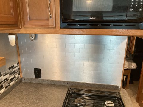 2015 Ford F-550 - Interior view of an RV kitchen a microwave above a tiled backsplash and stovetop.