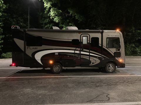 2015 Ford F-550 - Side view of a motorhome with dark and maroon graphics, parked outdoors at night.