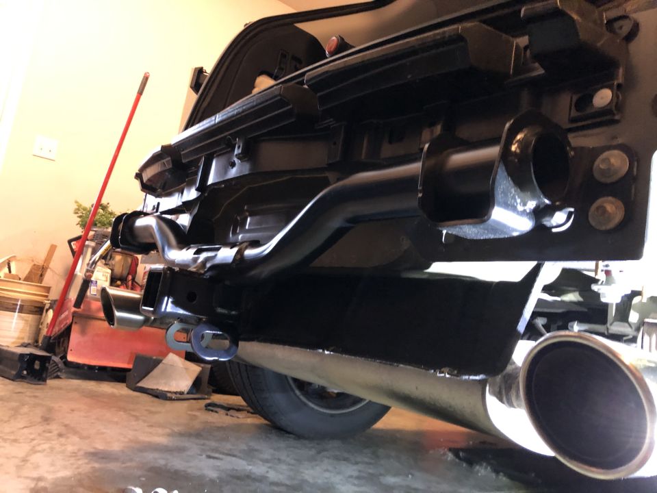 Rear view of a tow hitch receiver and exhaust pipe installed on a vehicle