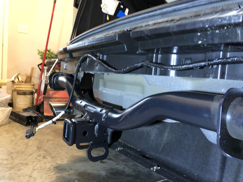 Black tow receiver hitch attached to vehicle frame, with wiring harness visible