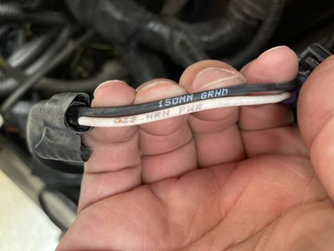 2015 Ford F-550 - Close-up of electrical wires with legible text, indicating ground and power for an air horn system.