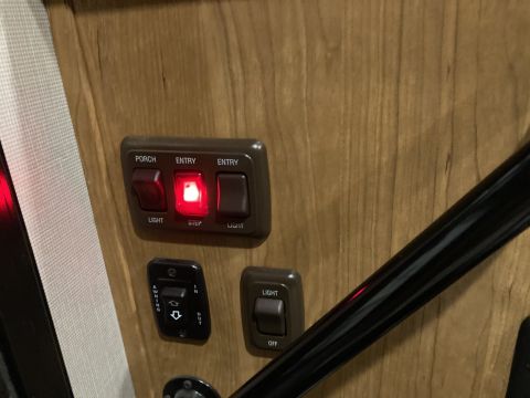 2015 Ford F-550 - Close-up of RV interior light switches, including one illuminated red for the step light.