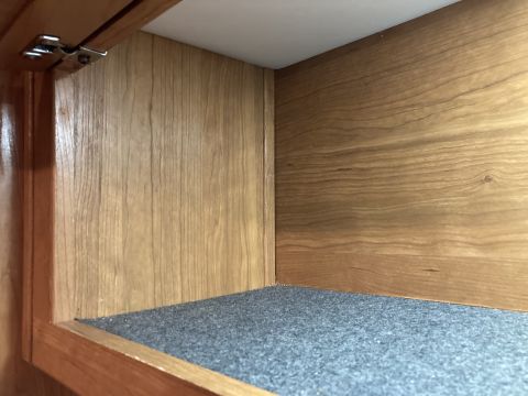 2015 Ford F-550 - Cabinet interior with wooden paneling, carpeted shelf, and visible hinge mechanism.