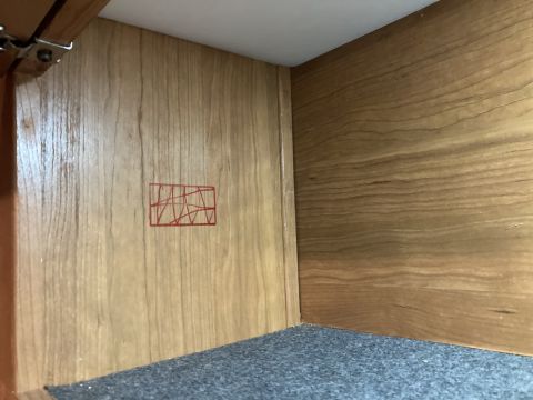 2015 Ford F-550 - A close-up view of the interior of a cabinet, showing wood grain paneling and a small, red, abstract geometric drawing.