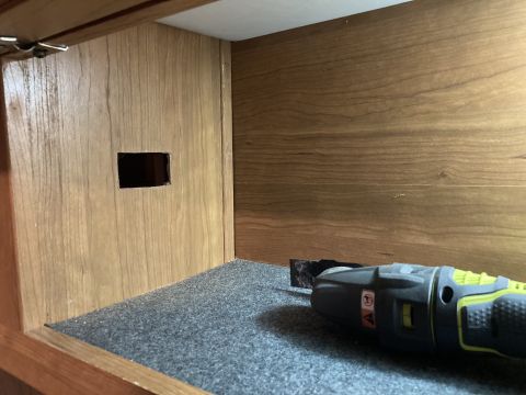 2015 Ford F-550 - Oscillating tool resting on carpet inside a wooden compartment with a square hole.