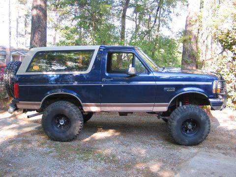 1995 Ford Bronco - This 1995 Ford Bronco is seen from the side, a blue body with tan trim and a spare tire mounted on the rear.
